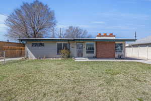 View of front facade featuring a front lawn, a patio area, and fence