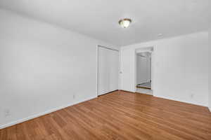 Spare room featuring baseboards, light wood-type flooring, and crown molding