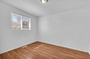 Empty room featuring baseboards, visible vents, and wood finished floors