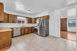 Kitchen featuring a sink, a wealth of natural light, brown cabinetry, and appliances with stainless steel finishes