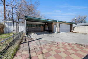 Garage with driveway, a carport, and fence
