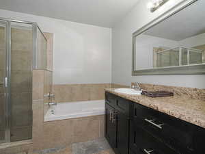 Bathroom featuring a bath, vanity, a textured ceiling, and a shower stall