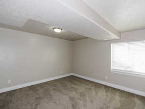 Carpeted spare room featuring baseboards and a textured ceiling