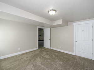 Interior space with baseboards, carpet floors, and a textured ceiling