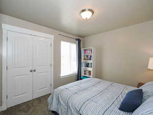 Bedroom featuring a closet, dark carpet, and a textured ceiling