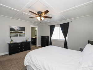 Carpeted bedroom with a ceiling fan, coffered ceiling, and baseboards
