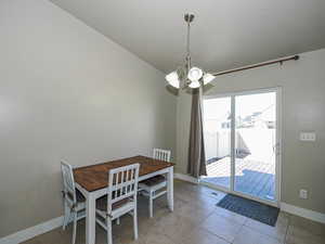Dining area with tile patterned floors, baseboards, a chandelier, and a textured ceiling