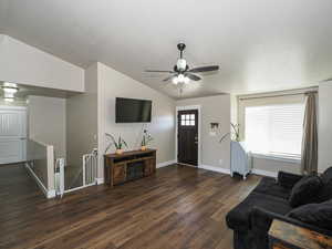 Living area with a textured ceiling, baseboards, a ceiling fan, dark wood finished floors, and lofted ceiling