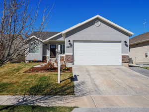 Ranch-style home featuring stone siding, an attached garage, concrete driveway, and stucco siding