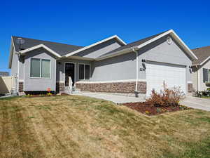 Ranch-style house with driveway, stone siding, stucco siding, an attached garage, and a front lawn
