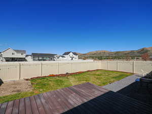 Deck featuring a fenced backyard, a residential view, a mountain view, and a yard