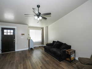 Living area featuring baseboards, dark wood-style flooring, and ceiling fan