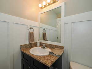 Bathroom with toilet, a decorative wall, and vanity
