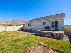Rear view of house featuring a lawn, a fenced backyard, a wooden deck, and a patio area