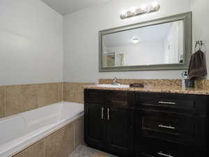 Bathroom featuring vanity, a shower with shower door, and a garden tub