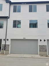 View of front of property with stone siding and a garage