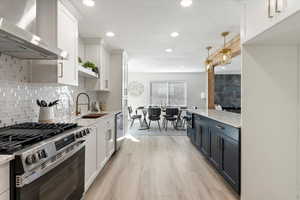 Kitchen featuring a sink, white cabinetry, appliances with stainless steel finishes, large island
