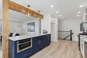 Kitchen with white cabinets, quartz countertops and blue cabinets with a drawer microwave