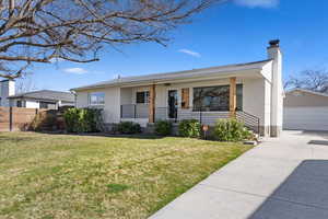 Ranch/rambler style house featuring an outbuilding,  front yard, covered porch, and a chimney