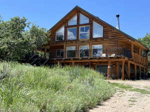 Back of property with driveway, a wooden deck, a garage, and log exterior