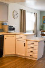 Kitchen featuring dark wood finished floors, light countertops, dishwasher, and stainless steel microwave