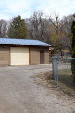 Garage featuring dirt driveway and fence