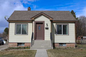 Bungalow featuring roof with shingles and a chimney