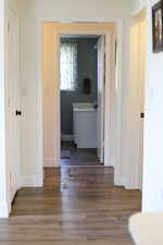 Corridor featuring baseboards, wood finished floors, and a sink
