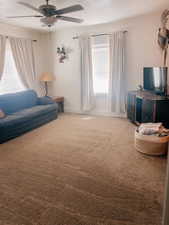 Living room featuring carpet flooring, a ceiling fan, and a textured ceiling