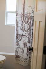 Bathroom featuring shower / bath combination with curtain and toilet
