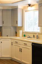Kitchen featuring dark wood-style flooring, light countertops, a sink, and dishwasher