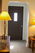 Entryway with arched walkways and carpet flooring
