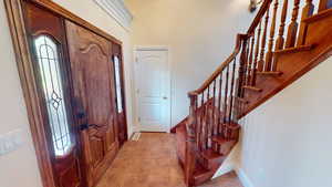 Entrance foyer with light tile patterned flooring and stairs