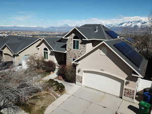 Traditional home featuring solar panels, stucco siding, stone siding, and a mountain view