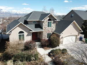 Traditional home featuring stone siding, roof with shingles, stucco siding, fence, and a mountain view