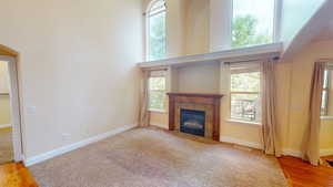 Unfurnished living room featuring healthy amount of natural light, a fireplace, and wood finished floors