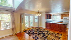 Kitchen featuring white appliances, a peninsula, a chandelier, light wood finished floors, and recessed lighting