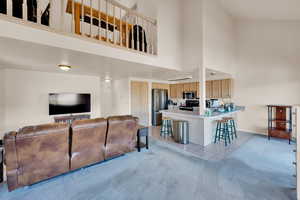 Living room featuring light carpet, baseboards, a towering ceiling, and light tile patterned floors
