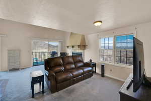 Carpeted living area with baseboards, a textured ceiling, and a fireplace