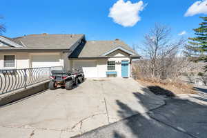View of property exterior with stucco siding, an attached garage, concrete driveway, and roof with shingles