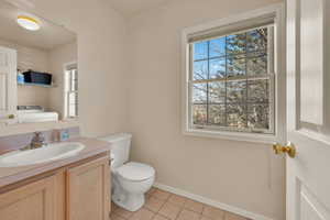 Half bath with tile patterned flooring, vanity, toilet, baseboards, and washer / clothes dryer