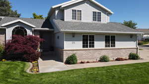 View of front of property featuring brick siding, a shingled roof, and a front lawn