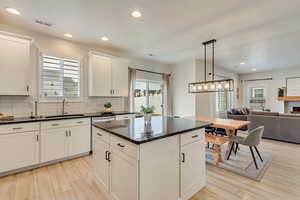 Kitchen featuring visible vents, light wood finished floors, a center island, a sink, and backsplash