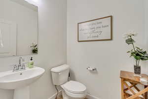 Bathroom featuring baseboards, toilet, and a sink