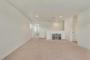 Below grade area featuring baseboards, visible vents, recessed lighting, and light colored carpet