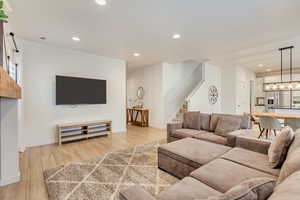 Living room with baseboards, stairs, recessed lighting, and light wood-type flooring