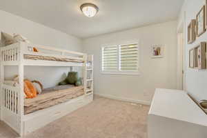 Bedroom with baseboards, light colored carpet, and visible vents
