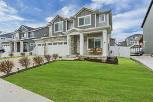 Craftsman inspired home featuring an attached garage, stone siding, board and batten siding, a residential view, and a gate
