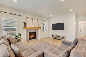 Living area with a glass covered fireplace, recessed lighting, and light wood-type flooring