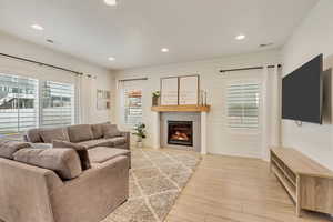 Living area with visible vents, a glass covered fireplace, recessed lighting, and wood finished floors